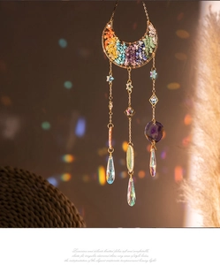 Detail of moon suncatcher with colorful natural stones and teardrop crystal prism