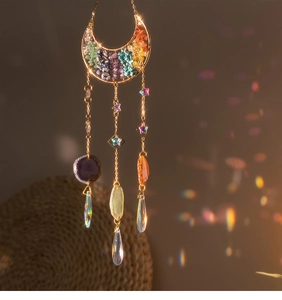Detail of crescent moon suncatcher with chakra stones and crystal prisms casting rainbow light