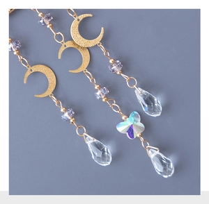 Detail of crystal suncatcher with moon metal charms and iridescent butterfly pendant