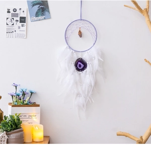 Dettaglio dell'acchiappasogni boho viola con piume bianche e fetta di agata naturale