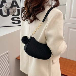 Chic black V-quilted underarm bag with gold chain strap and plush pom-pom detail