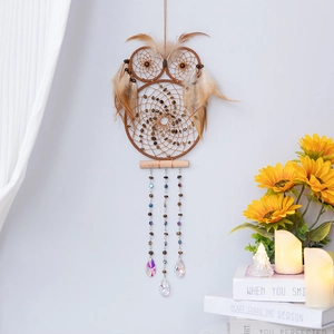 Handmade brown owl dream catcher with feathers and crystal drops on a warm wall