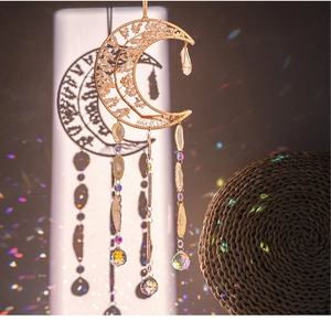 Macro shot of moon-shaped wire pendant with pink crystal chips and rainbow lens flare