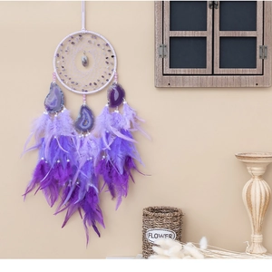 Detail of dream catcher featuring purple feathers, agate slices, and amethyst stones