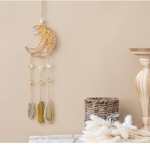 Detail of moon-shaped crystal wall hanging with yellow stones and agate slice decor