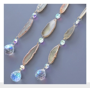 Detail of natural agate slice and faceted crystal bead hanging with golden metal ring