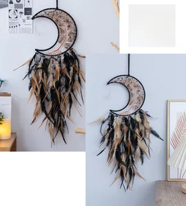Artistic moon-shaped dream catcher with stones and feathers hung on a white wall decor