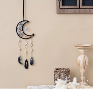 Moon shaped crystal dream catcher with black frame and hanging agate slices on a wall