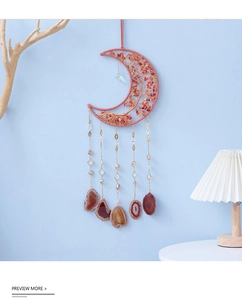 Detail of pink crystal moon dreamcatcher with agate slices on a light blue wall