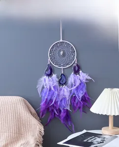 Bohemian purple dream catcher with agate slices and feathers on a cozy bedroom wall