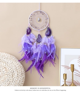 Detailed view of handmade purple dreamcatcher with agate stones and natural feathers