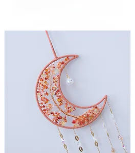 Detail of moon-shaped dream catcher with pink weaving, red stones and crystal prism pendant