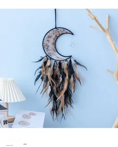 Detail of moon-shaped dream catcher with metal tree of life and black feathers