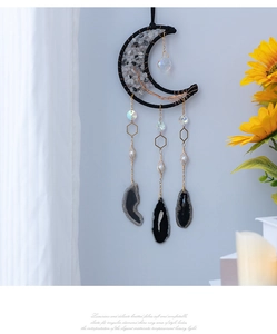 Macro detail of crescent moon wall hanging with white crystals and agate stone pendants