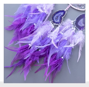 Detailed view of purple feathers and natural agate slices on a dreamcatcher hanging ornament