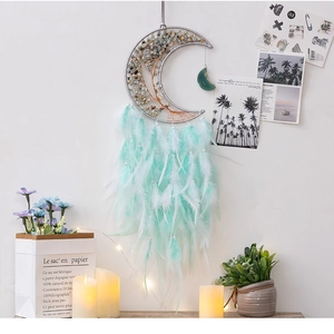 Moon-shaped dreamcatcher with life tree amethyst and mint green feathers hanging on a white wall