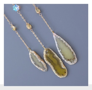 Macro shot of long agate slice pendants with golden chains and blue floral beads