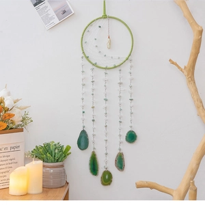 Detail of hand-woven half-moon dreamcatcher with green agate slices and natural stones