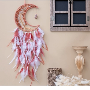 Moon shaped dream catcher with crystal tree of life and pink feathers in home setting