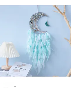 Detail of moon-shaped dreamcatcher with blue natural stones and gradient feathers
