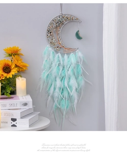 Detail of moon-shaped dreamcatcher wall decor with life tree wire wrap and mint green feathers