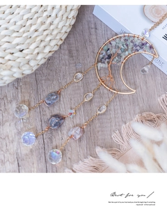 Detail of moon tree of life suncatcher with green and purple crystals in gold wire frame