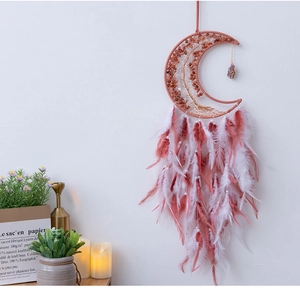 Detail of moon-shaped dream catcher with crystal tree of life and pink feathers
