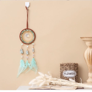 Detail of dream catcher wall decor with mint green feathers and turquoise beads