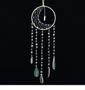 Detail of hand-woven half moon dreamcatcher with green agate stone slices and beaded tassels