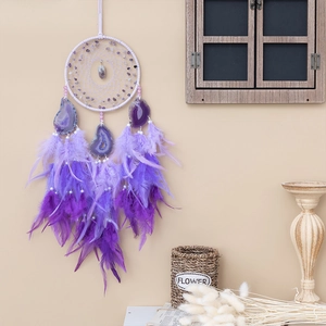 Purple dream catcher with amethyst stones agate slices and feathers on a beige wall