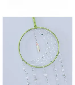 Detailed view of woven crystal dreamcatcher with green stones and hanging quartz pendant