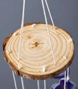 Detail of natural wood slice with tree bark and woven ropes for wind chime hanging