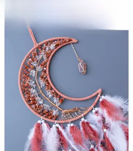 Detailed view of moon-shaped dream catcher with life tree wire art and peach feathers