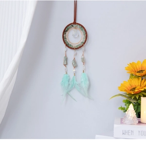 Detail of handmade turquoise dreamcatcher with green feathers and natural gemstones