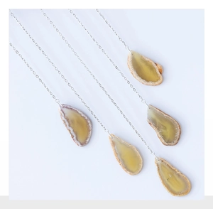 Close-up of translucent yellow agate slices and raw stone pendants on silver chains