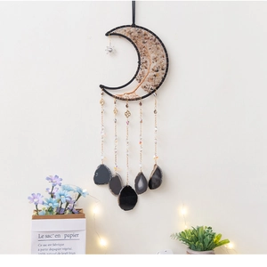 Detail of moon-shaped dream catcher with crushed stones and hanging agate slices