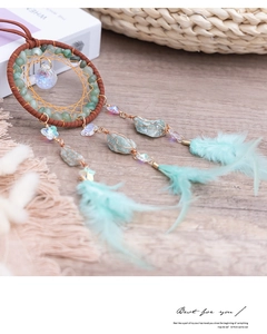 Detail view of turquoise dream catcher with green feathers and crystal ball pendant