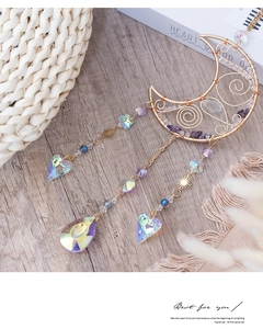 Macro shot of a moon-shaped suncatcher with purple amethyst and rainbow crystal pendants