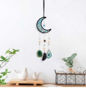 Détail de décoration murale lune bohème avec pierres bleu-vert et chaînes dorées