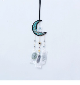 Détail de l'attrape-rêves en forme de lune avec pierres turquoise, chaînes et étoiles