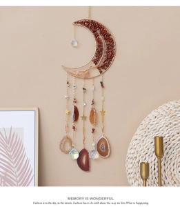 Détail d'un attrape-soleil en forme de lune avec pierres rouges et pendentifs étoiles