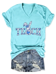 Close-up of blue V-neck T-shirt featuring a floral rabbit print and TEACH text detail