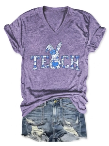 Flat lay of purple V-neck T-shirt with blue floral TEACH print and ripped denim shorts