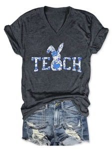 Flat lay of gray V-neck tee with floral TEACH bunny print and ripped denim shorts