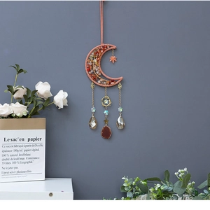 Detail of moon-shaped crystal dreamcatcher with red stones and gold chain ornaments