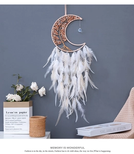 Detail of tree of life design inside moon-shaped dream catcher with white feathers