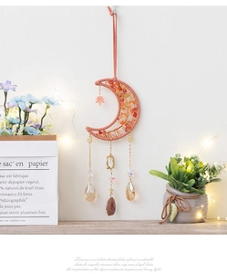 Detail of moon-shaped dream catcher hanging on a wall with crystal stones and warm lights