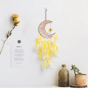 Detail of moon-shaped dream catcher with woven lace, yellow feathers and sunflower pendant