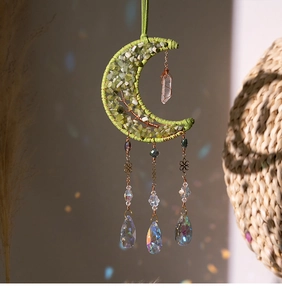 Detailed view of moon suncatcher with green stones and faceted crystal teardrop prism
