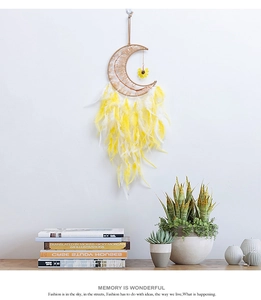 Detail of Boho moon dreamcatcher with yellow feathers hanging on a white wall decor